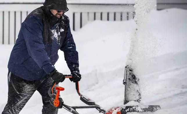 Chris Crowley struggles with heavy, wet snow Sunday afternoon, Feb. 16, 2025, as wind and driving sleet made conditions difficult to remove snow from a driveway on Shawmut Street in Lewiston, Maine. (Russ Dillingham/Sun Journal via AP)