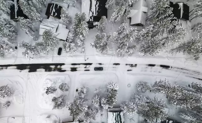 A car drives in the Tahoe-Donner neighborhood after an overnight winter storm in Truckee, Calif., Friday, Feb. 14, 2025. (Stephen Lam/San Francisco Chronicle via AP)