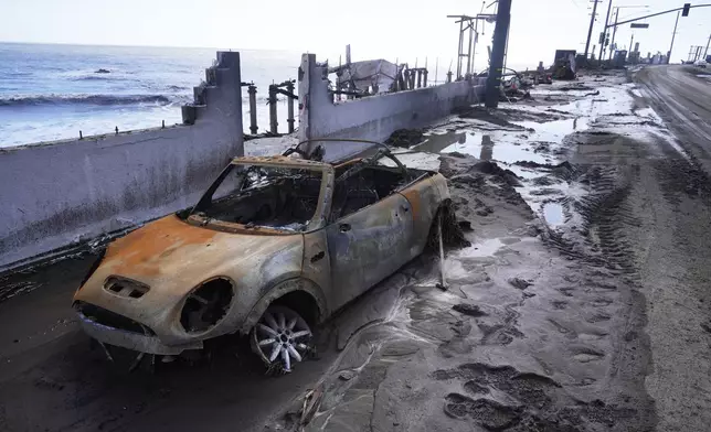 A fire-damages vehicle is left in front of a beach front property after a storm Friday, Feb. 14, 2025, in Malibu, Calif. (AP Photo/Damian Dovarganes)