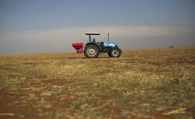FILE- A farm employee spreads fertilizer on the farm of John Rankin, a commercial farmer producing Maze and Corn on an industrial level, in Gerdau, North West province, South Africa, Nov. 19, 2018. (AP Photo/Jerome Delay, File)