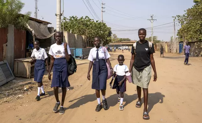 Schoolgirls walk back home after being turned away from their school due to an ongoing extreme heatwave that has caused some students to collapse in Juba, South Sudan Friday, Feb. 21, 2025. (AP Photo/Florence Miettaux)