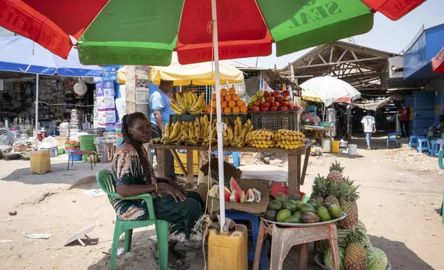 Modong Celina, a fruit seller sits under an umbrella in Juba, South Sudan Friday, Feb. 21, 2025. (AP Photo/Florence Miettaux)