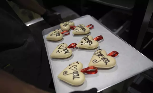 A worker holds chocolate Valentine hearts on a drying tray in the workshop at The Chocolate Line in Bruges, Belgium, Thursday, Feb. 6, 2025. (AP Photo/Virginia Mayo)