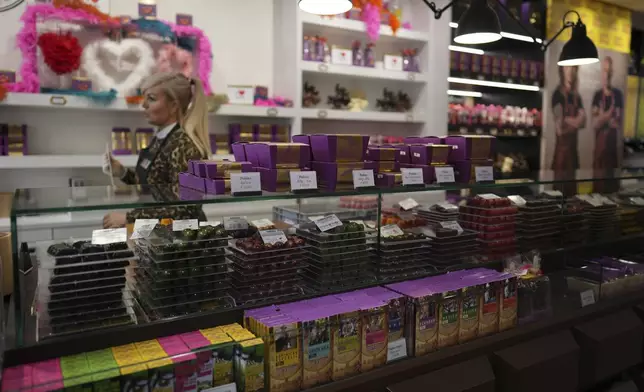 A saleswoman walks by boxes of artisan chocolates at The Chocolate Line in Bruges, Belgium, Thursday, Feb. 6, 2025. (AP Photo/Virginia Mayo)