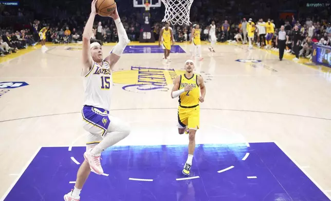 Los Angeles Lakers guard Austin Reaves, left, dunks as Indiana Pacers guard Andrew Nembhard watches during the second half of an NBA basketball game Saturday, Feb. 8, 2025, in Los Angeles. (AP Photo/Mark J. Terrill)