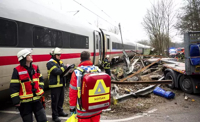 Emergency services stand at the scene of an accident at a level crossing, a collision between a train and a truck, in Hamburg, Germany, Tuesday Feb. 11, 2025. (Daniel Bockwoldt/dpa via AP)