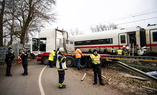 Emergency services stand at the scene of an accident at a level crossing, a collision between a train and a truck, in Hamburg, Germany, Tuesday Feb. 11, 2025. (Daniel Bockwoldt/dpa via AP)