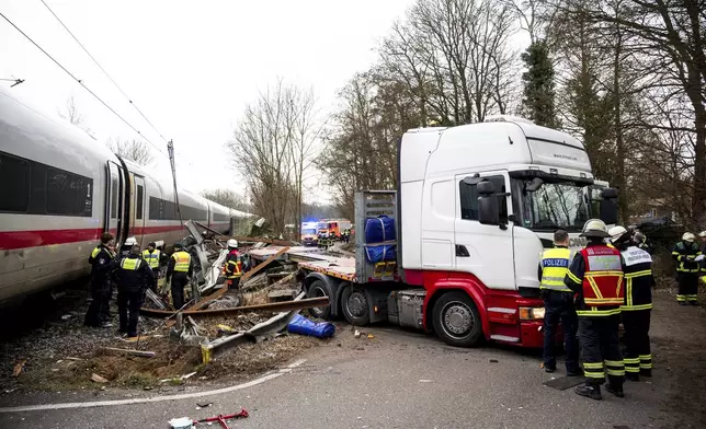 Emergency services stand at the scene of an accident at a level crossing, a collision between a train and a truck, in Hamburg, Germany, Tuesday Feb. 11, 2025. (Daniel Bockwoldt/dpa via AP)