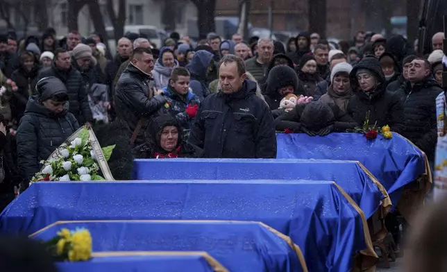 Relatives stand near coffins of Kateryna Zapishnya, 38, Diana Zapishnya, 12, Danyil Zapishnyi, 8, Serhii Zapishnyi, 40, Dmytro Yavorskyi, 37, Sofia Yavorska, 9, and Olena Yavorska 38, who were killed on Feb. 1 by a Russian strike on residential building during a funeral ceremony in Poltava, Ukraine, Wednesday, Feb. 5, 2025. (AP Photo/Evgeniy Maloletka)