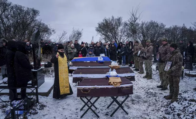 A priest blesses coffins of Kateryna Zapishnya, 38, Diana Zapishnya, 12, Danyil Zapishnyi, 8, and Serhii Zapishnyi, 40, who were killed on Feb. 1 by a Russian strike on residential building of Poltava, during a funeral ceremony in Dykanka, Ukraine, Wednesday, Feb. 5, 2025. (AP Photo/Evgeniy Maloletka)