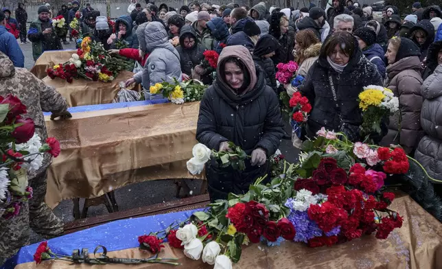 People come to say goodbye to Kateryna Zapishnya, 38, Diana Zapishnya, 12, Danyil Zapishnyi, 8, Serhii Zapishnyi, 40, Dmytro Yavorskyi, 37, Sofia Yavorska, 9, and Olena Yavorska 38, who were killed on Feb. 1 by a Russian strike on residential building during a funeral ceremony in Poltava, Ukraine, Wednesday, Feb. 5, 2025. (AP Photo/Evgeniy Maloletka)