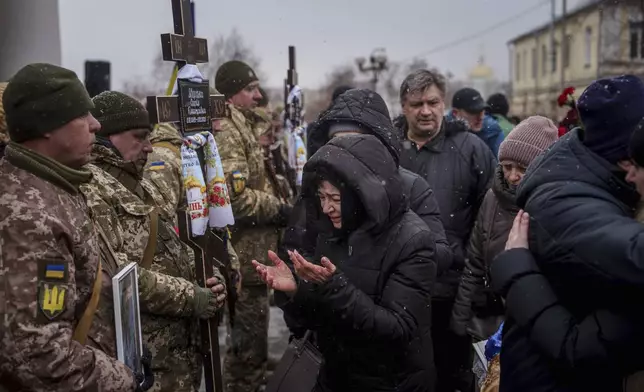 A woman cries as she says goodbye to Dmytro Yavorskyi, 37, Sofia Yavorska, 9, Olena Yavorska 38, who were killed on Feb. 1 by a Russian strike on residential building during a funeral ceremony in Poltava, Ukraine, Wednesday, Feb. 5, 2025. (AP Photo/Evgeniy Maloletka)
