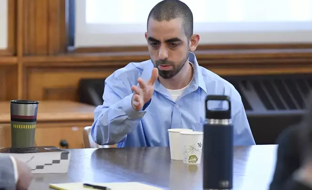 Hadi Matar, right, charged with severely injuring author Salman Rushdie in a 2022 knife attack, speaks to his defense team in Chautauqua County court in Mayville, N.Y., Monday, Feb. 10, 2025. (AP Photo/Adrian Kraus)