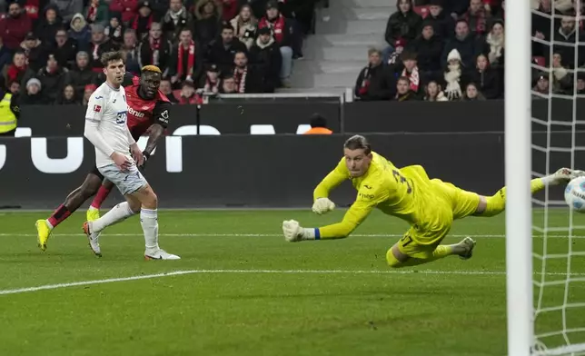 Leverkusen's Victor Boniface scores the opening goal against Hoffenheim's goalkeeper Luca Philipp during the German Bundesliga soccer match between Bayer Leverkusen and TSG Hoffenheim at the BayArena in Leverkusen, Germany, Sunday, Feb. 2, 2025. (AP Photo/Martin Meissner)