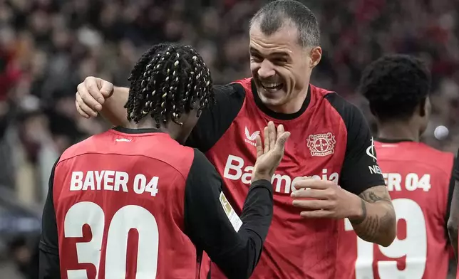 Leverkusen's Jeremie Frimpong is celebrated by Leverkusen's Granit Xhaka after he scored his side's second goal during the German Bundesliga soccer match between Bayer Leverkusen and TSG Hoffenheim at the BayArena in Leverkusen, Germany, Sunday, Feb. 2, 2025. (AP Photo/Martin Meissner)