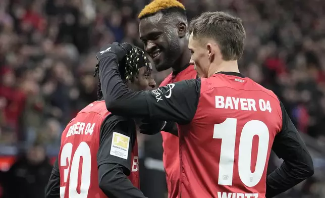 Leverkusen's Jeremie Frimpong, left, celebrates with teammates Victor Boniface and Florian Wirtz after he scored his side's second goal during the German Bundesliga soccer match between Bayer Leverkusen and TSG Hoffenheim at the BayArena in Leverkusen, Germany, Sunday, Feb. 2, 2025. (AP Photo/Martin Meissner)