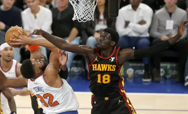 New York Knicks center Karl-Anthony Towns (32) and Atlanta Hawks forward Mouhamed Gueye (18) battle for the ball during the first half of an NBA basketball game Wednesday, Feb. 12, 2025, in New York. (AP Photo/John Munson)