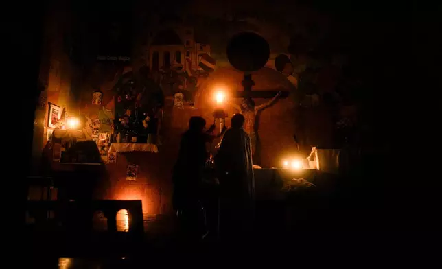 Father Lorenzo de Vedia, better known as "Toto," center right, arrives for evening Mass where he offered up prayers for the good health of Pope Francis, amid a power outage in Buenos Aires, Argentina, Saturday, Feb. 22, 2025. (AP Photo/Natacha Pisarenko)