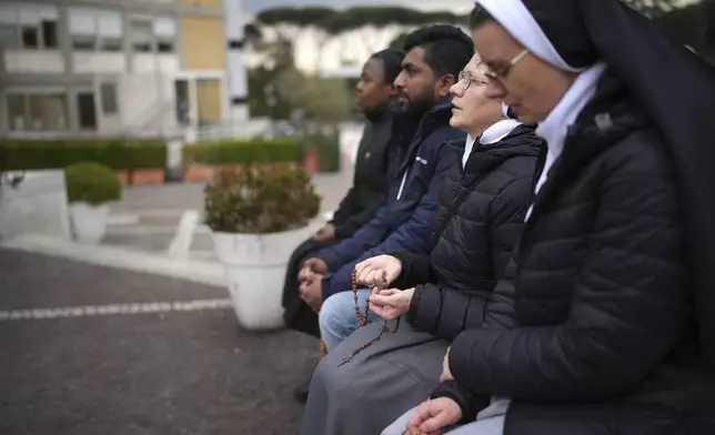 Nuns pray for Pope Francis in front of the statue of Pope John Paul II at the Agostino Gemelli Polyclinic, in Rome, Thursday, Feb. 20, 2025, where the Pontiff is hospitalized since Friday, Feb. 14. (AP Photo/Alessandra Tarantino)