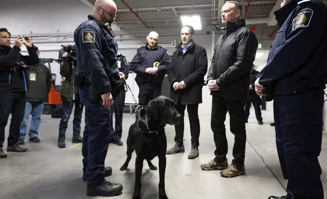 Denver, a Canada Border Services Agency narcotics detection dog, is seen during a tour of the CBSA Lansdowne port of entry in Lansdowne, Ontario, with Minister of Public Safety David McGuinty, right, and Canada's fentanyl czar Kevin Brosseau, center right, Wednesday, Feb. 12, 2025. (Spencer Colby/The Canadian Press via AP)