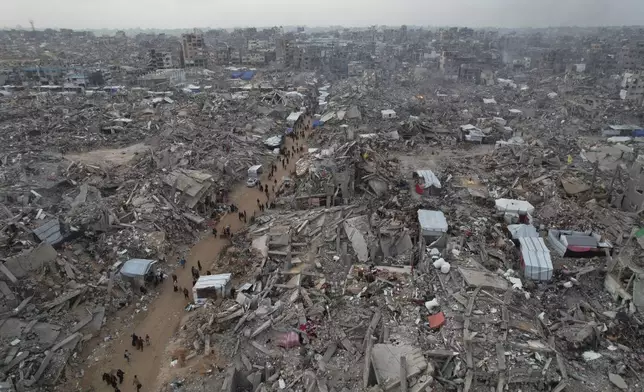 An aerial photograph taken by a drone shows people walking between the destruction caused by the Israeli air and ground offensive in Jabaliya, Gaza Strip, on Sunday, Feb. 16, 2025. (AP Photo/Mohammad Abu Samra)