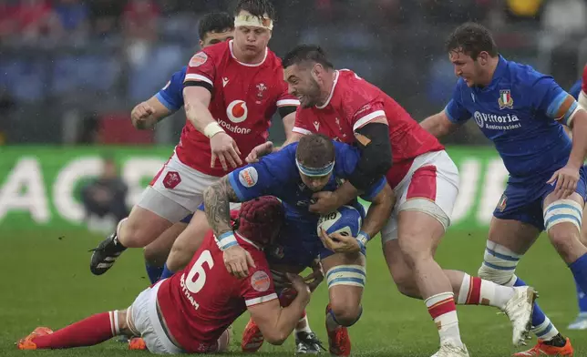 Italy's Lorenzo Cannone, center, is tackled by defenders during the Six Nations rugby union match between Italy and Wales at the Olympic Stadium in Roma, Italy, Saturday, Feb. 8, 2025. (AP Photo/Alessandra Tarantino)