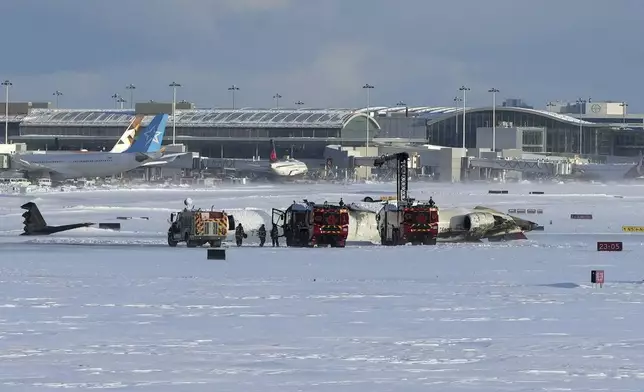 Pearson International Airport firefighters work on an upside down Delta Air Lines plane, which was heading from Minneapolis to Toronto when it crashed on the runway, in Toronto, Monday, Feb. 17, 2025. (Teresa Barbieri/The Canadian Press via AP)