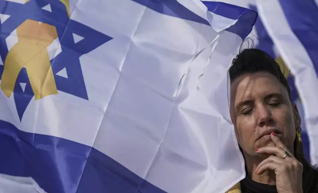 A woman reacts at the so-called 'Hostages Square' in Tel Aviv, Israel, Thursday, Feb. 20, 2025, as the bodies of four Israeli hostages, including a mother and her two children, are handed over by Hamas to the Red Cross in Gaza. (AP Photo/Oded Balilty)