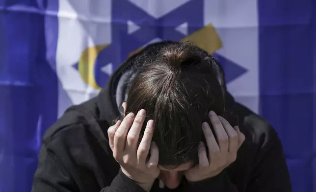 A woman reacts at the so-called 'Hostages Square' in Tel Aviv, Israel, Thursday, Feb. 20, 2025, as the bodies of four Israeli hostages, including a mother and her two children, are handed over by Hamas to the Red Cross in Gaza. (AP Photo/Oded Balilty)
