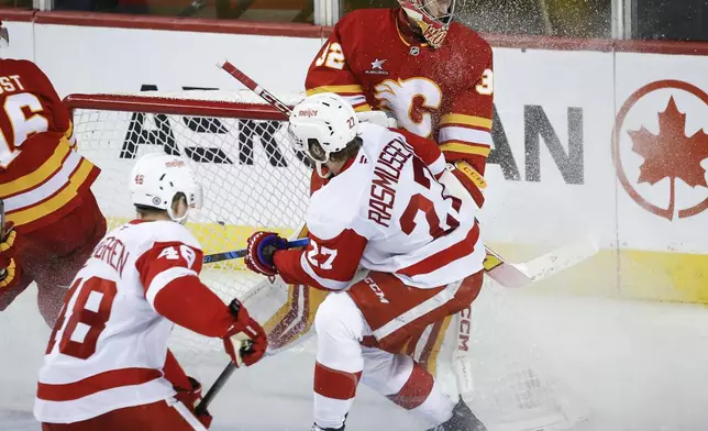 Detroit Red Wings' Michael Rasmussen (27) collides with Calgary Flames goalie Dustin Wolf during the third period of an NHL hockey game in Calgary, Alberta, Saturday, Feb. 1, 2025. (Jeff McIntosh/The Canadian Press via AP)