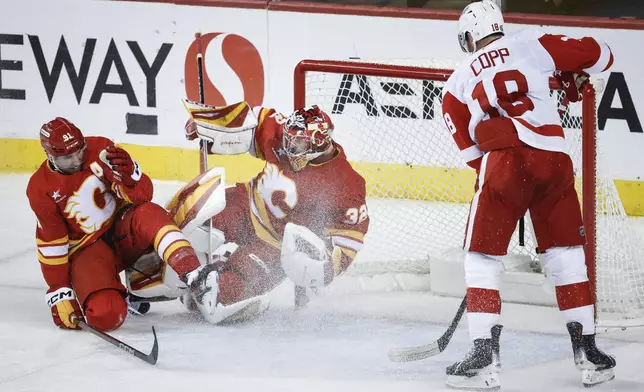 Detroit Red Wings' Andrew Copp, right, looks on as Calgary Flames' Nazem Kadri, left, crashes into goalie Dustin Wolf during the third period of an NHL hockey game in Calgary, Alberta, Saturday, Feb. 1, 2025. (Jeff McIntosh/The Canadian Press via AP)