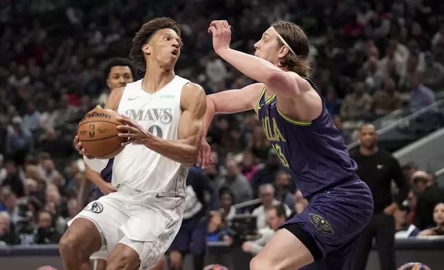 Dallas Mavericks forward Kessler Edwards, left, looks to pass the ball as New Orleans Pelicans' Kelly Olynyk, right, defends in the first half of an NBA basketball game in Dallas, Friday, Feb. 21, 2025. (AP Photo/Tony Gutierrez)