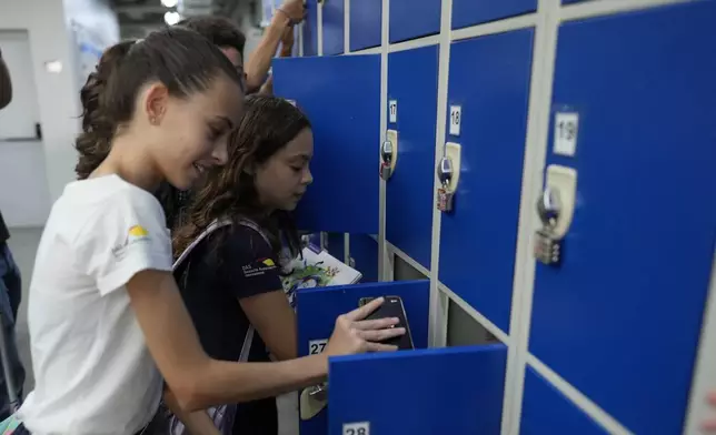 Students store their mobile phones in lockers at Porto Seguro School in Sao Paulo, Thursday, Feb. 6, 2025, as they head to class under a new law that forbids their use in schools. (AP Photo/Andre Penner)