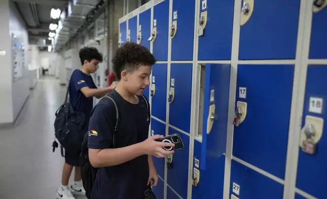 Students store their mobile phones in lockers as they head to class under a new law restricting their use on campus at Porto Seguro School in Sao Paulo, Thursday, Feb. 6, 2025.. (AP Photo/Andre Penner)