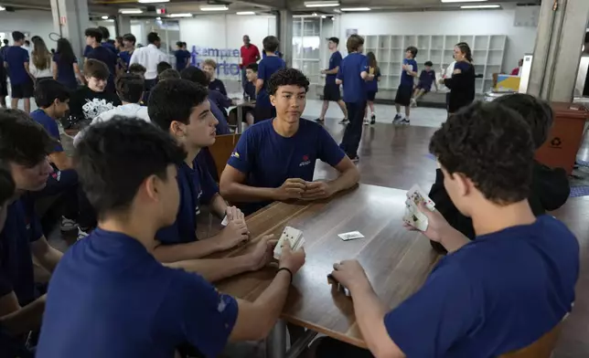 Students play cards during recess in their first week at school under a new law that forbids the use of mobile phones on campus, at Porto Seguro School in Sao Paulo, Thursday, Feb. 6, 2025. (AP Photo/Andre Penner)