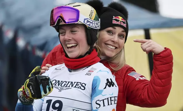 United States' A.J. Hurt and United States' Lindsey Vonn, right, smile at the finish area of a slalom run of a women's team combined event, at the Alpine Ski World Championships, in Saalbach-Hinterglemm, Austria, Tuesday, Feb. 11, 2025. (AP Photo/Marco Trovati)