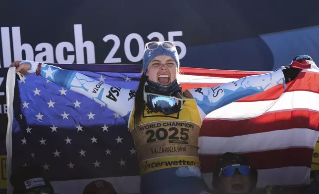 United States' Breezy Johnson celebrates on the podium after winning the gold medal in a women's downhill race, at the Alpine Ski World Championships, in Saalbach-Hinterglemm, Austria, Saturday, Feb. 8, 2025. (AP Photo/Giovanni Auletta)