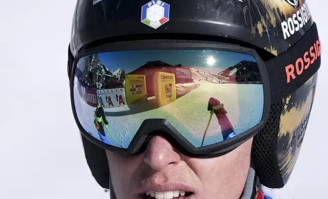 The finish area is reflected in the goggles of Italy's Federica Brignone after she completed an alpine ski, women's World Championship downhill training, in Saalbach-Hinterglemm, Austria, Tuesday, Feb. 4, 2025. (AP Photo/Giovanni Auletta)