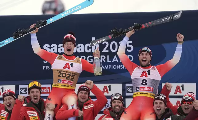 Gold medalist in a men's downhill race Switzerland's Franjo von Allmen, left, and bronze medalist Switzerland's Alexis Monney, celebrate with the team, at the Alpine Ski World Championships, in Saalbach-Hinterglemm, Austria, Sunday, Feb. 9, 2025. (AP Photo/Giovanni Auletta)