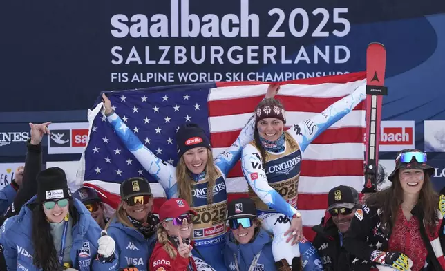 United States' Mikaela Shiffrin, left, and United States' Breezy Johnson, celebrate on the podium with the team after winning the gold medal in a women's team combined event, at the Alpine Ski World Championships, in Saalbach-Hinterglemm, Austria, Tuesday, Feb. 11, 2025. (AP Photo/Giovanni Auletta)