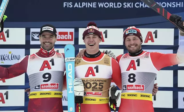 Switzerland's Franjo von Allmen, center, winner of a gold medal in a men's downhill race, celebrates on the podium with silver medalist Austria's Vincent Kriechmayr, left, and bronze medalist Switzerland's Alexis Monney, at the Alpine Ski World Championships, in Saalbach-Hinterglemm, Austria, Sunday, Feb. 9, 2025. (AP Photo/Giovanni Auletta)