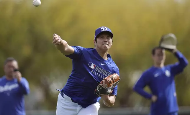 Los Angeles Dodgers' Shohei Ohtani, of Japan, warms up with other pitchers and catchers at the Dodgers baseball spring training facility, Tuesday, Feb. 11, 2025, in Phoenix. (AP Photo/Ross D. Franklin)