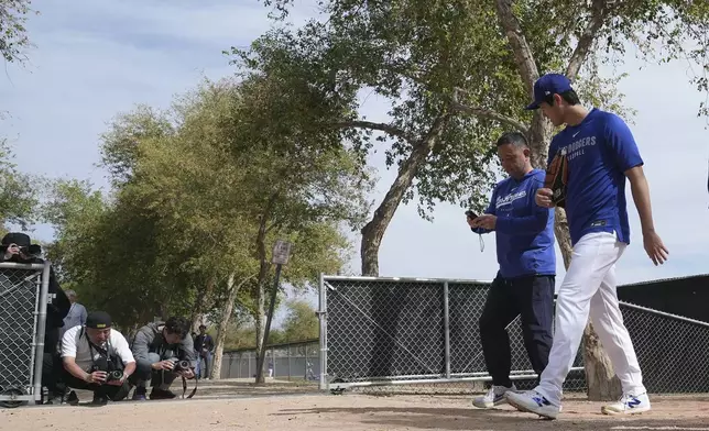 Los Angeles Dodgers' Shohei Ohtani, right, of Japan, walks back to the clubhouse at the Dodgers baseball spring training facility after working out Tuesday, Feb. 11, 2025, in Phoenix. (AP Photo/Ross D. Franklin)