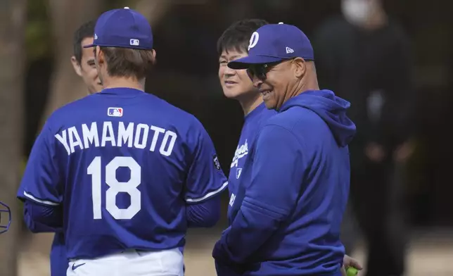 Los Angeles Dodgers pitcher Yoshinobu Yamamoto (18), of Japan, gets a smile out of Dodgers manager Dave Roberts, right, after Yamamoto's pitching session at the Dodgers baseball spring training facility Tuesday, Feb. 11, 2025, in Phoenix. (AP Photo/Ross D. Franklin)