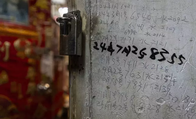 Handwritten notes of the water bill are seen on the wall outside a subdivided flat in Sham Shui Po district of Hong Kong, on Feb. 6, 2025. (AP Photo/Chan Long Hei)
