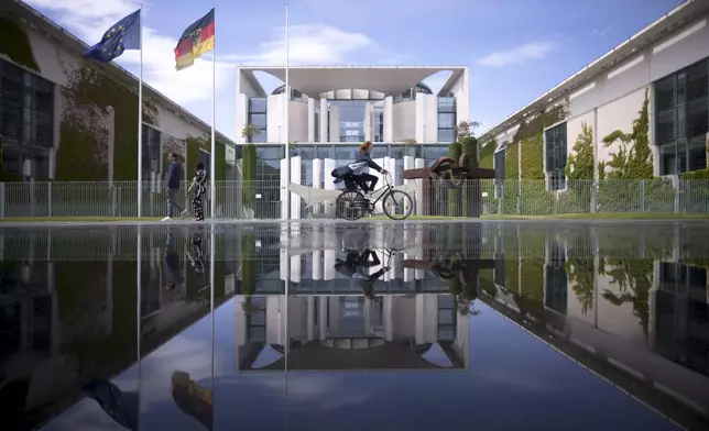 FILE - The Chancellery with the office of the German chancellors reflected in a puddle from a sprinkler on a sunny day in Berlin, Germany, June 13, 2023. (AP Photo/Markus Schreiber), File