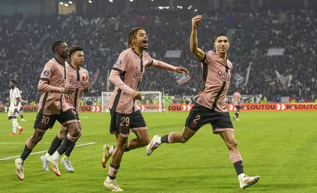 PSG's Achraf Hakimi, right, celebrates with teammates after scoring opening goal during the French League One soccer match between Lyon and Paris Saint-Germain at the Groupama stadium, outside Lyon, France, Sunday, Feb. 23, 2025. (AP Photo/Laurent Cipriani)