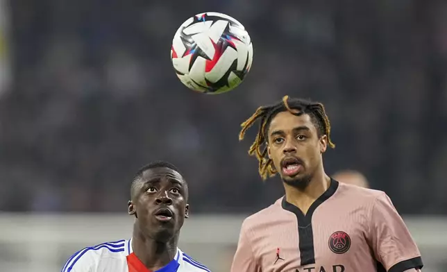 Lyon's Sael Kumbedi, left, duels for the ball with PSG's Bradley Barcola during the French League One soccer match between Lyon and Paris Saint-Germain at the Groupama stadium, outside Lyon, France, Sunday, Feb. 23, 2025. (AP Photo/Laurent Cipriani)