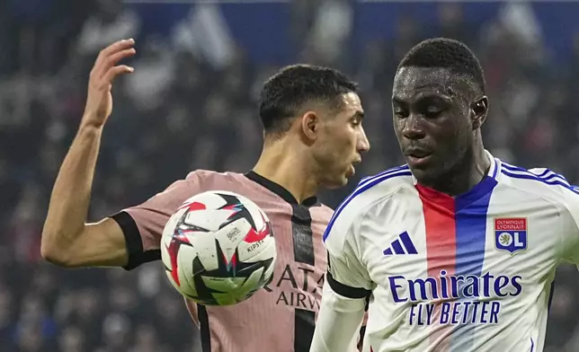 Lyon's Moussa Niakhate, right, duels for the ball with PSG's Achraf Hakimi during the French League One soccer match between Lyon and Paris Saint-Germain at the Groupama stadium, outside Lyon, France, Sunday, Feb. 23, 2025. (AP Photo/Laurent Cipriani)