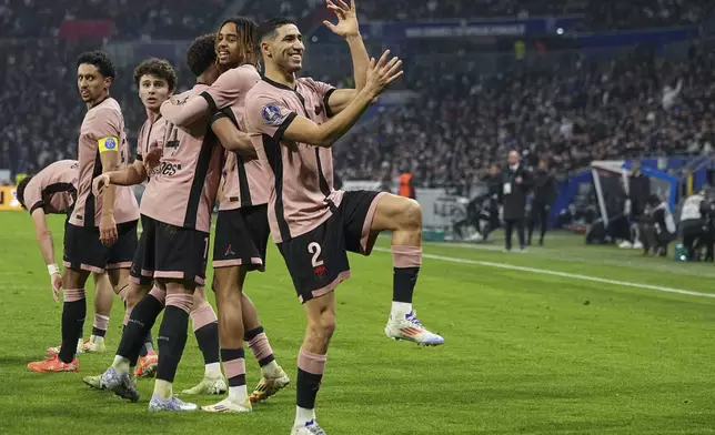 PSG's Achraf Hakimi, front, celebrates with teammates after scoring opening goal during the French League One soccer match between Lyon and Paris Saint-Germain at the Groupama stadium, outside Lyon, France, Sunday, Feb. 23, 2025. (AP Photo/Laurent Cipriani)
